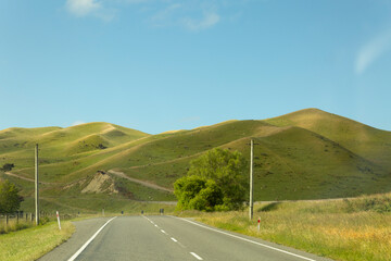 open road with green hills and blue skies