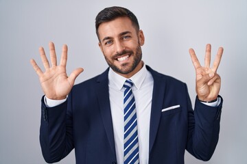 Handsome hispanic man wearing suit and tie showing and pointing up with fingers number eight while smiling confident and happy.