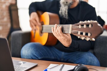 Middle age grey-haired man musician having online classical guitar class at music studio