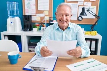 Middle age grey-haired man business worker reading document at office
