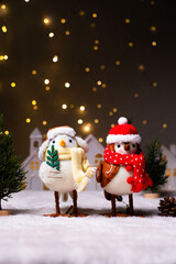 Cute Christmas birds with winter outfits in the snowy village for a happy Christmas background and greeting card.