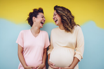 Two cute pregnant women with happy smiling faces standing outdoor and laugh.