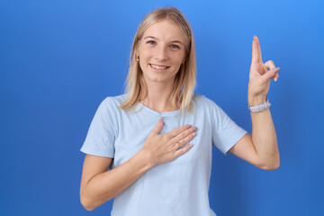 Young caucasian woman wearing casual blue t shirt smiling swearing with hand on chest and fingers...