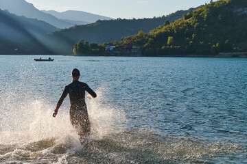 Triathlon athlete starting swimming training on lake