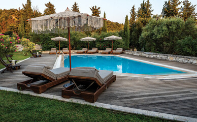 Swimming pool and beds for relaxing in summer. Swimming pool in the nature among greenery.