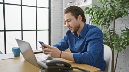 Young hispanic man business worker using laptop and smartphone at the office