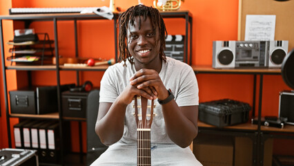 African american man musician smiling confident holding guitar at music studio