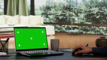 Rich entrepreneur rests at his outstanding alpine villa, viewing greenscreen projection on his laptop. International director interacts on pc with blank chromakey display, luxurious daily living.
