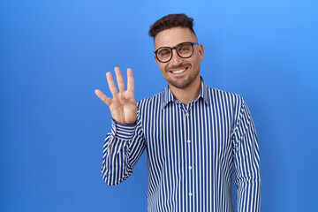 Naklejka premium Hispanic man with beard wearing glasses showing and pointing up with fingers number four while smiling confident and happy.