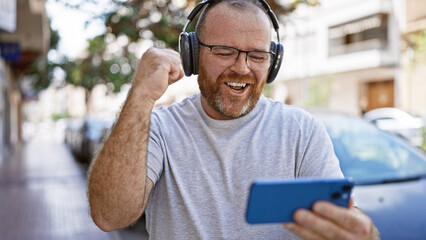 Caucasian man watching video on smartphone celebrating at street