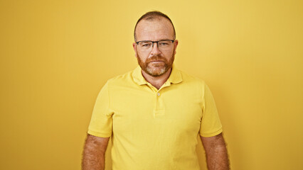 Caucasian man standing with serious expression over isolated yellow background