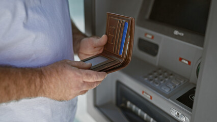 Handsome middle-aged caucasian man making a credit card transaction at a street atm. captivating...