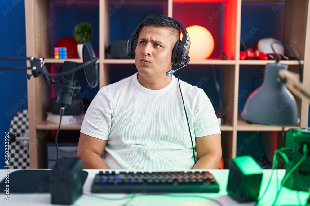 Canvas Prints young hispanic man playing video games smiling looking to the side and staring away thinking.