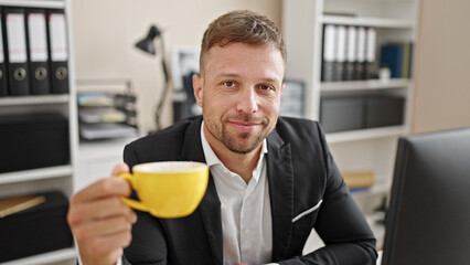 Young man business worker drinking coffee smiling at office