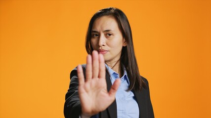Filipino woman showing stop sign with palm, advertising negativity and no symbol on camera. Female...