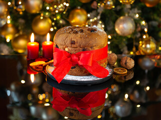 Italian Christmas cake Panettone with a red bow on a black glass against the background of a...