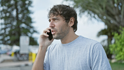 Portrait of a handsome, young guy, with blond beard talking on his phone, deep in concentration....
