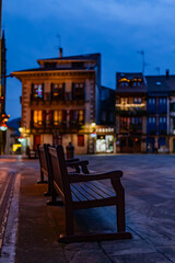 Solitary bench adorned for Christmas, urban bokeh, winter ambiance in Hondarribia square.