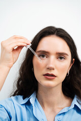 Girl is applying hyaluronic serum with pipette on face. Young woman with acid dropper is applying drops of acid on her skin.
