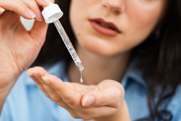 Girl with hyaluronic acid or serum pipette in hands close-up. Young woman is applying moisturizing...