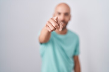 Middle age bald man standing over white background pointing displeased and frustrated to the camera, angry and furious with you