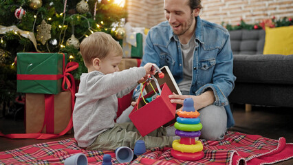 Father and son unpacking christmas gift playing with toys at home