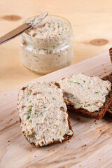 Wooden cutting board showcasing black bread accompanied by pate and fresh greens creating appealing composition
