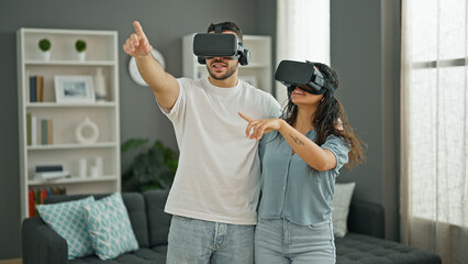 Man and woman couple playing video game using virtual reality glasses at home