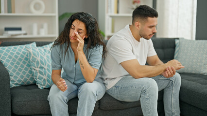 Fototapeta na wymiar Man and woman couple sitting on sofa arguing stressed at home