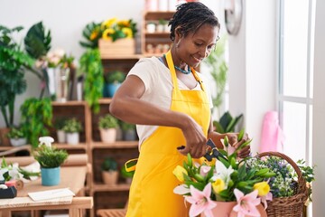 Middle age african american woman florist cutting plants at flower shop - Powered by Adobe
