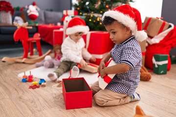Fototapeta na wymiar Adorable boys celebrating christmas unpacking gift at home