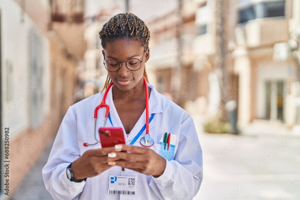 Wall mural African american woman doctor smiling confident using smartphone at street