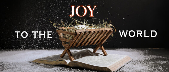 Manger with dummy of baby, Holy Bible and snow on dark background. Concept of Christmas story - obrazy, fototapety, plakaty