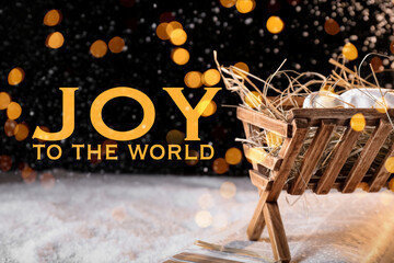 Manger with dummy of baby, Holy Bible and snow on dark background. Concept of Christmas story