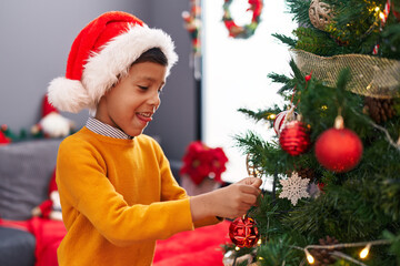 Adorable hispanic boy smiling confident decorating christmas tree at home