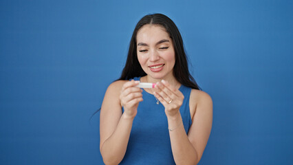 Fototapeta na wymiar Young beautiful hispanic woman holding pregnancy test smiling over isolated blue background