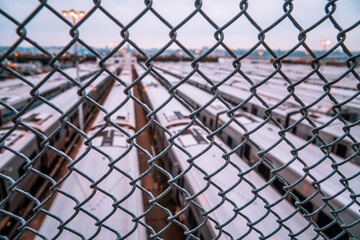 A train depot yard behind a fence in New York City at sunset 