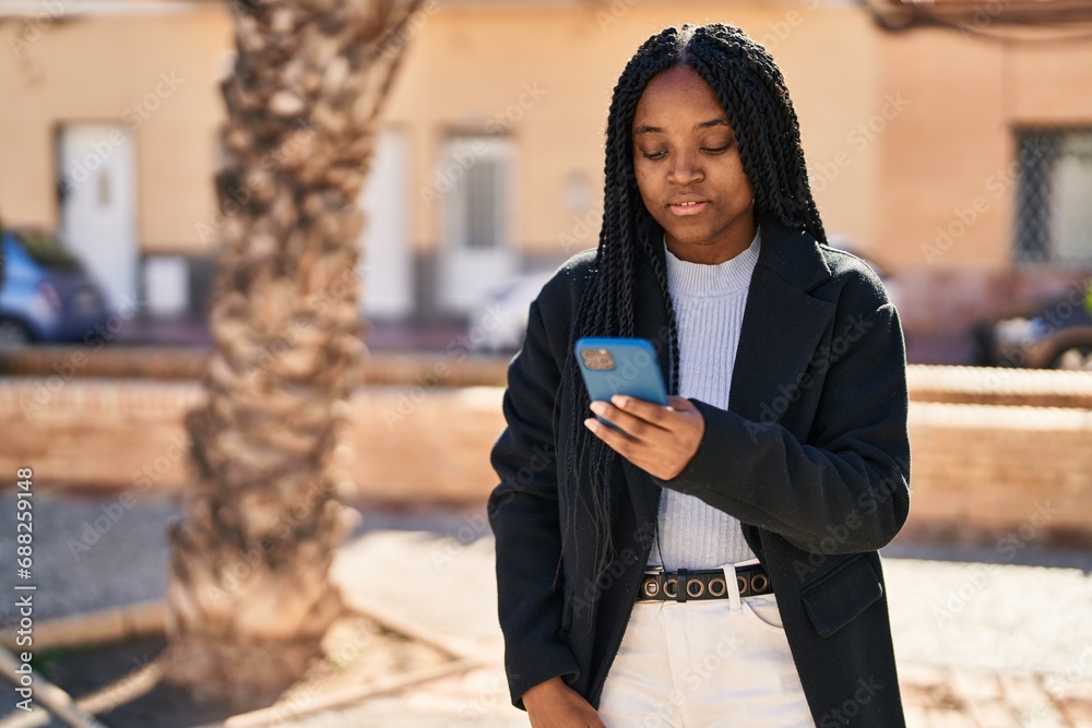 Poster African american woman using smartphone with serious expression at park