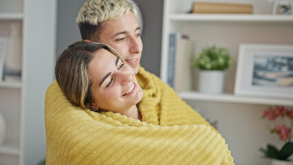 Beautiful couple covering with blanket hugging each other at home