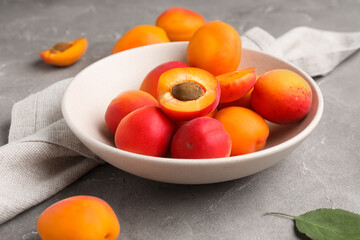 Bowl with sweet apricots on grey background