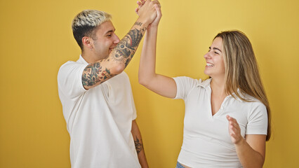 Beautiful couple smiling confident high five celebrating over isolated yellow background