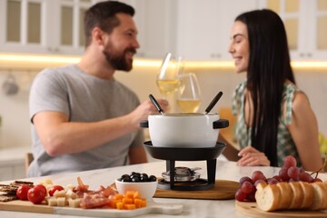 Couple spending time together during romantic date in kitchen, focus on fondue