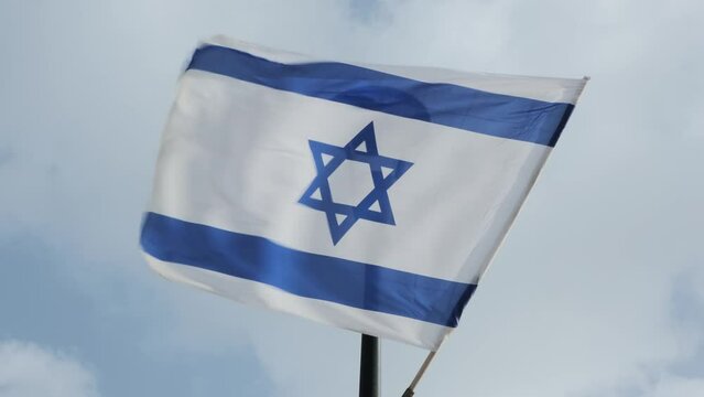 Israeli flag, adorned with the iconic Magen David star, proudly waves against the backdrop of a stormy sky,  patriotic image on a turbulent day.