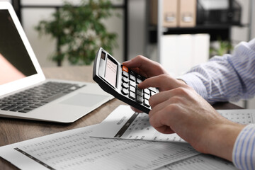 Man using calculator at table in office, closeup