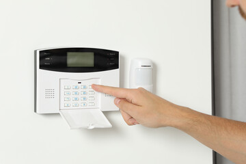 Man entering code on home security system indoors, closeup