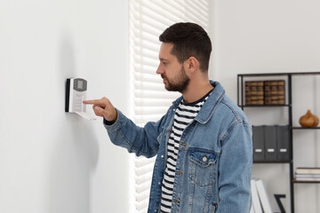 Man entering code on home security system indoors - obrazy, fototapety, plakaty