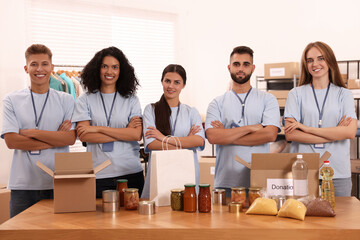 Portrait of volunteers and food products at table in warehouse