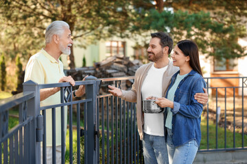 Fototapeta premium Friendly relationship with neighbours. Happy couple and senior man near fence outdoors