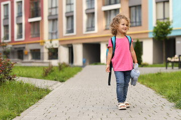 Happy girl with toy walking to kindergarten outdoors. Space for text