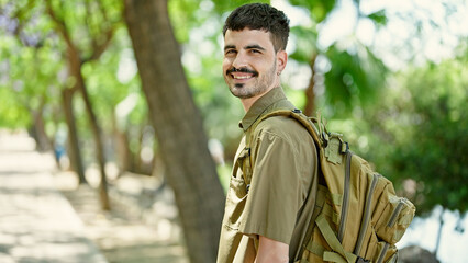 Young hispanic man tourist wearing backpack smiling at park